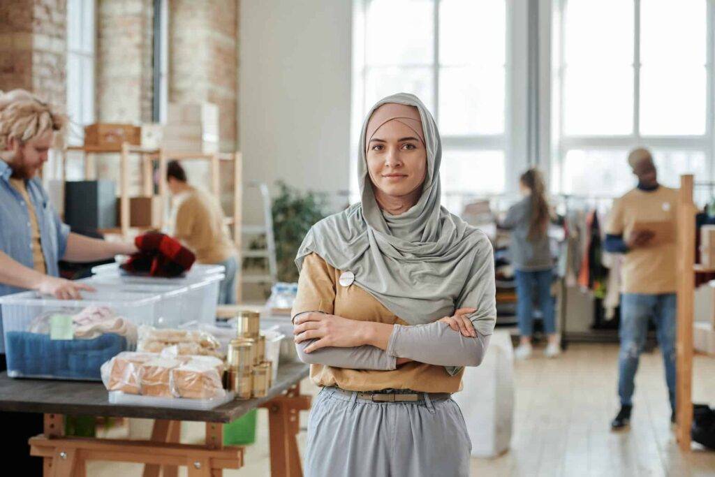 Woman Wearing a Hijab on the Background of People Sorting Clothing